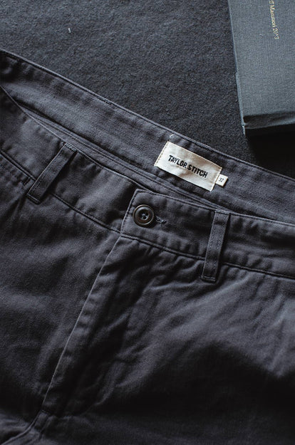 A pair of Foundation Pants folded on a black background, showing the back pocket.