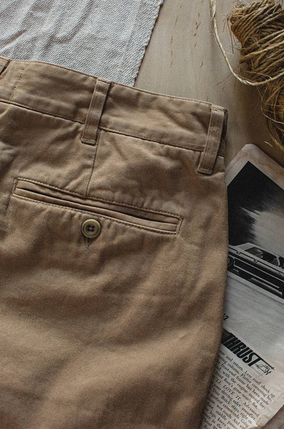 A pair of Foundation Pants folded on a black background, showing the back pocket.