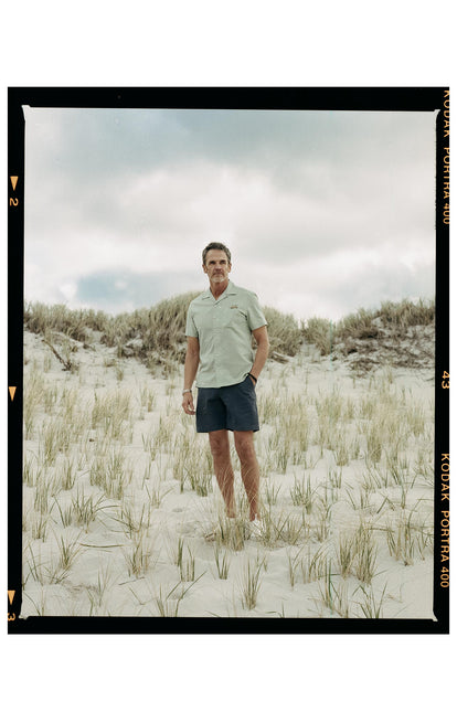 fit model posing on the beach wearing The Short Sleeve Hawthorne in Sea Moss Floral