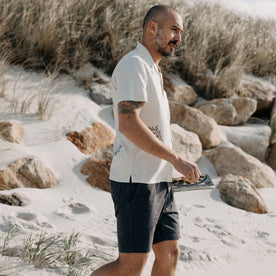 fit model walking on the beach wearing The Apres Short in Organic Dark Blue Foundation Twill