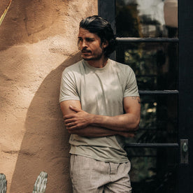 fit model leaning against the wall wearing The Cotton Hemp Tee in Sage