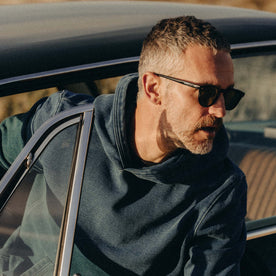 fit model coming out of a car wearing The Apres Hoodie in Washed Indigo Terry